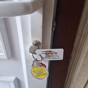 Euro lock changed on white upvc door showing Longridge Locksmiths Ltd key tag with company details 